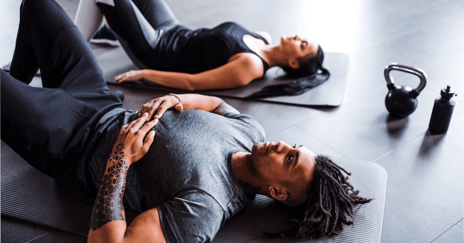 Coach accompagnant une cliente sur un mouvement d'épaules en salle de musculation