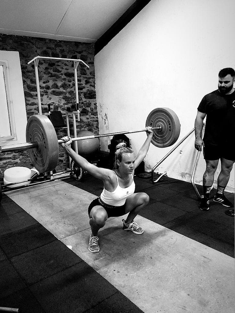 Maxime Labardin encadrant une cliente sur un squat overhead en salle de musculation